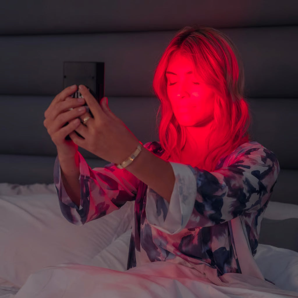 A woman using her Vital Charge red light therapy device to sleep better and treat chronic pain